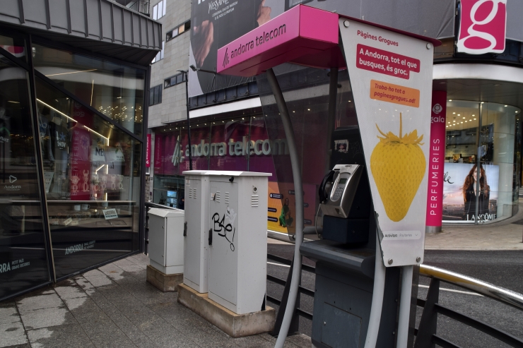 Una cabina telefònica amb la seu de l'empresa Andorra Telecom al fons.